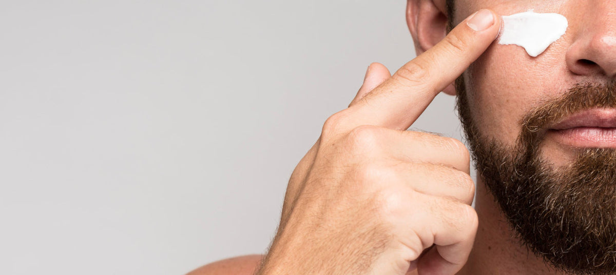 Een man smeert dagcrème voor mannen op zijn gezicht