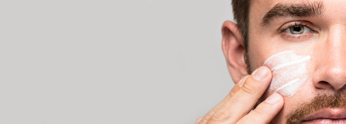 Een man smeert anti aging crème voor mannen op zijn gezicht