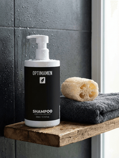 OPTIMAMEN Keratin Volume Boost Shampoo fles met pompje op een marmeren wastafel naast een opgerolde grijze handdoek en een groen plantje in een moderne badkamer.